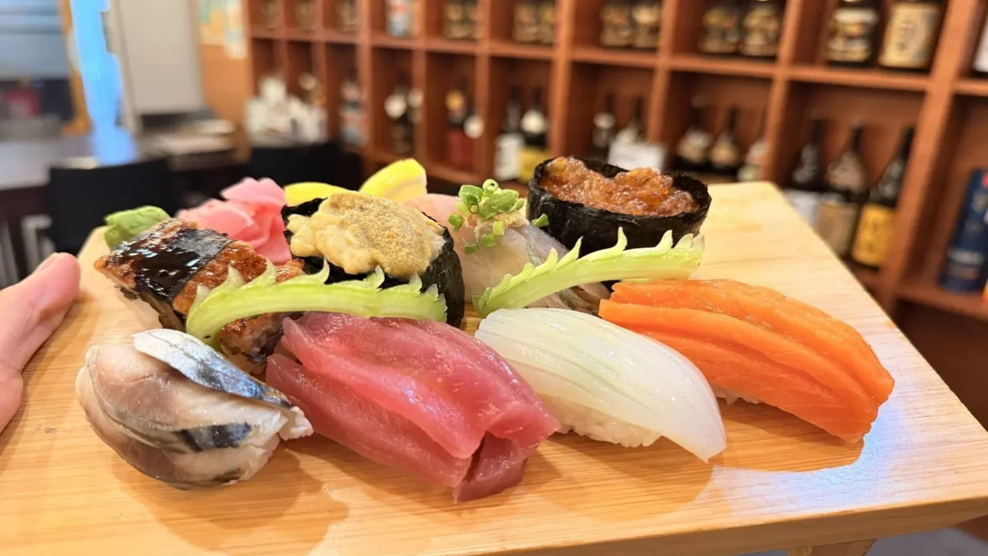 Assorted nigiri and gunkan sushi with salmon, tuna, squid, mackerel, eel, uni, and fish roe served on a wooden platter.